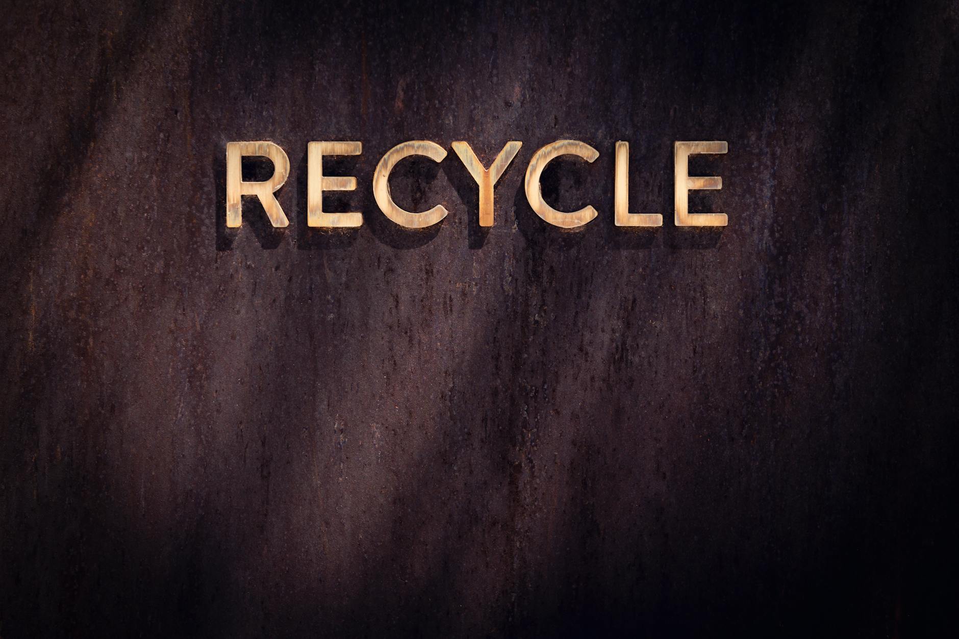 Recykling metali szlachetnych w technologii: jak odzyskuje się złoto z biżuterii Złoty symbol recyklingu na drewnianej ścianie, idea eko w jubilerstwie